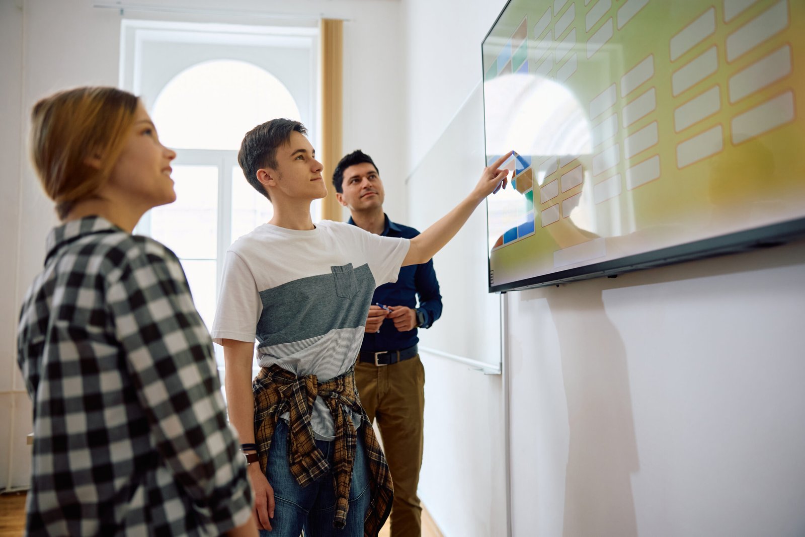 High school students and their teacher using interactive whiteboard during a class.