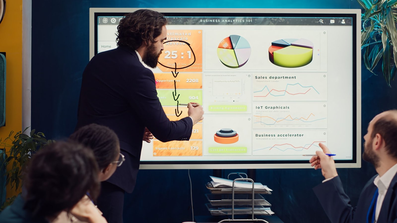 Project manager does a market research presentation for his team, better understanding of the situation. Associates work on technology or infrastructure investments to fulfill objectives. Camera A.