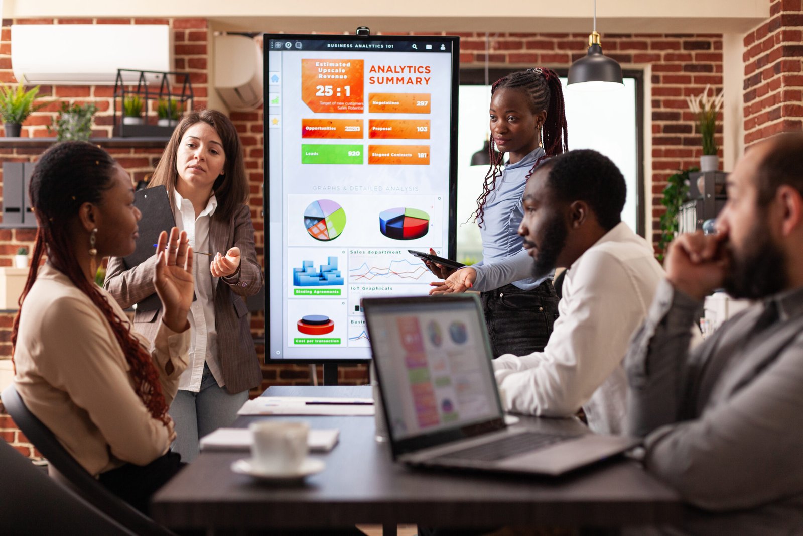 Diverse colleagues working at marketing presentation analyzing financial graph in startup company office. Entrepreneurs team brainstorming project ideas at workplace. Business start-up concept